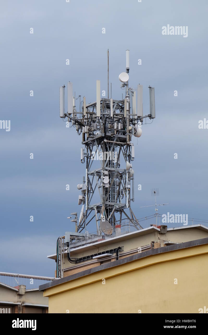 Cellular phone antenna on the roof of a building - Saving money on condo fees - Condominium series - Harmful mobile phone tower against a grey sky Stock Photo