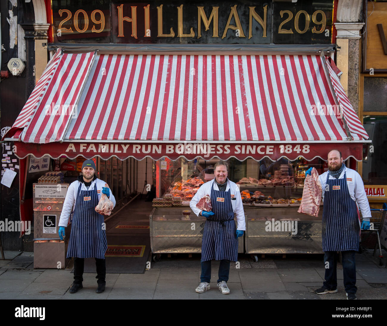 Butchers pose outside their butcher shop in London Stock Photo