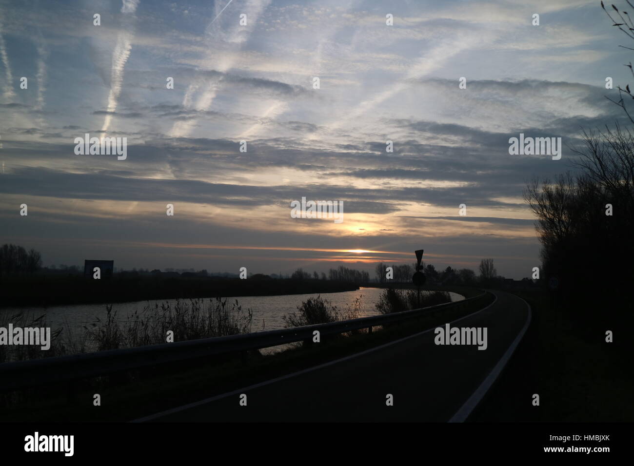 sun behind clouds reflecting on water Stock Photo