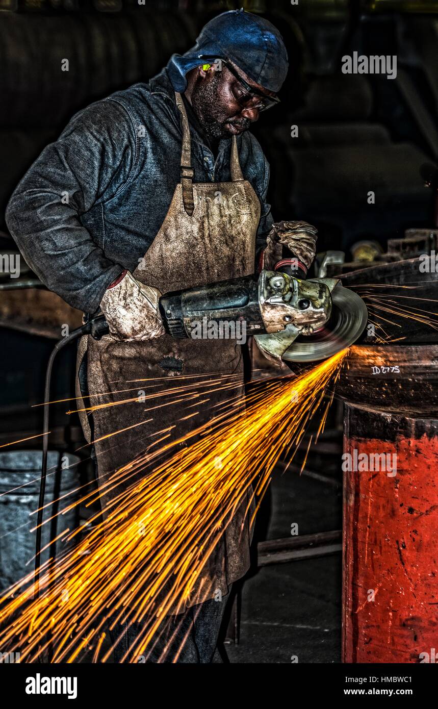A artisan in an industrial uses a heavy duty grinding machine