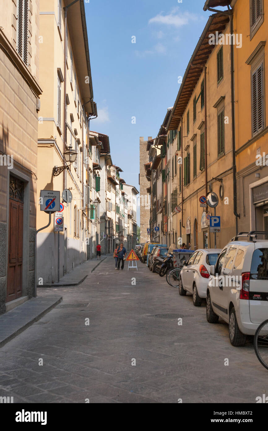 FLORENCE, ITALY - SEPTEMBER 09, 2014: Unrecognized pedestrians walk along city narrow street with parked cars and motorbikes. Florence is the administ Stock Photo
