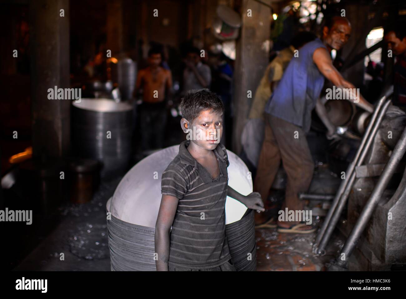 Portrait a Bnagladeshi child labor who work in a silver cooking pot factory in Dhaka. Children as young as teen operate heavy machinery unaided, Stock Photo