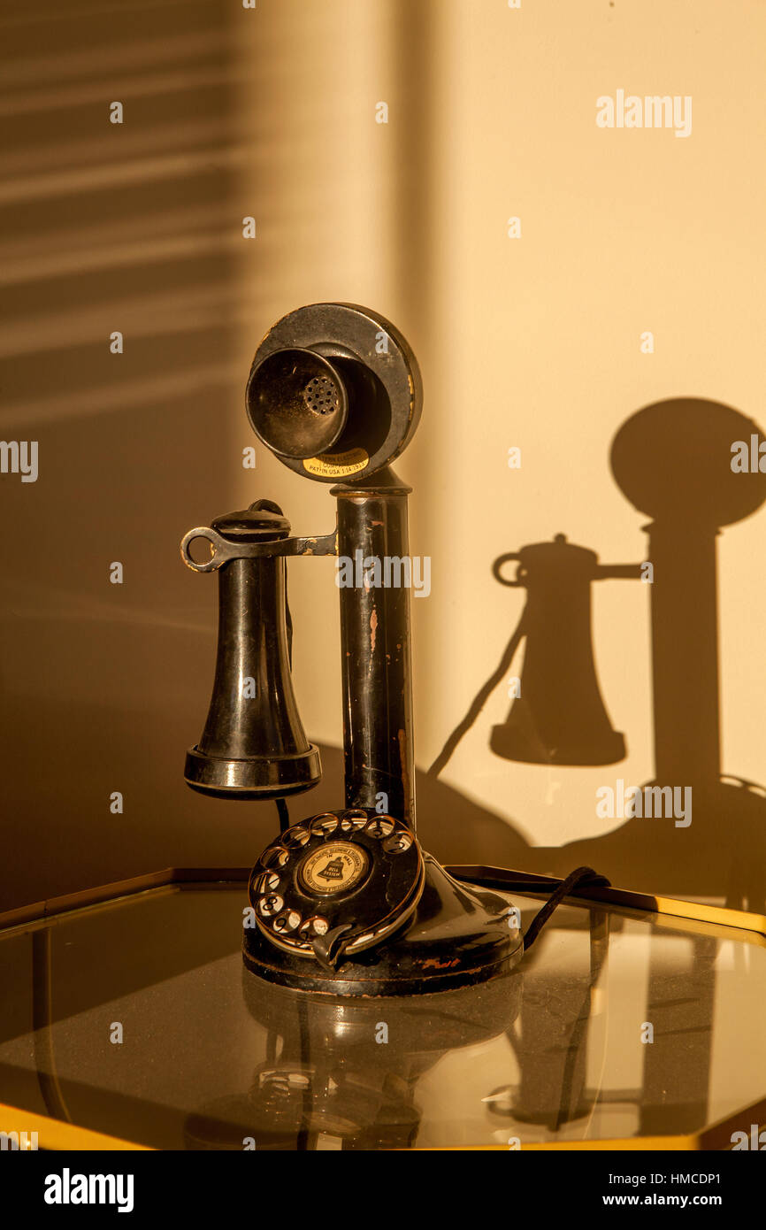 An old fashioned black candlestick telephone with rotary dial sits on a