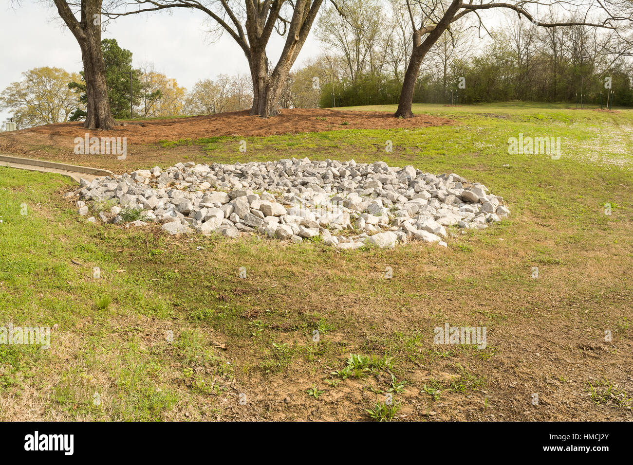 A manmade, concrete, watershed with a strategically placed pile of rocks to slow the runoff of water and minimize erosion. Stock Photo