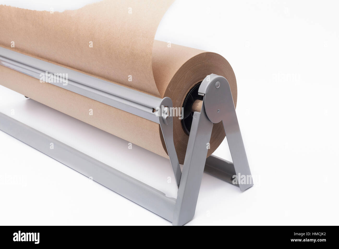 Roll of brown craft paper and paper cutter on a white background Stock Photo