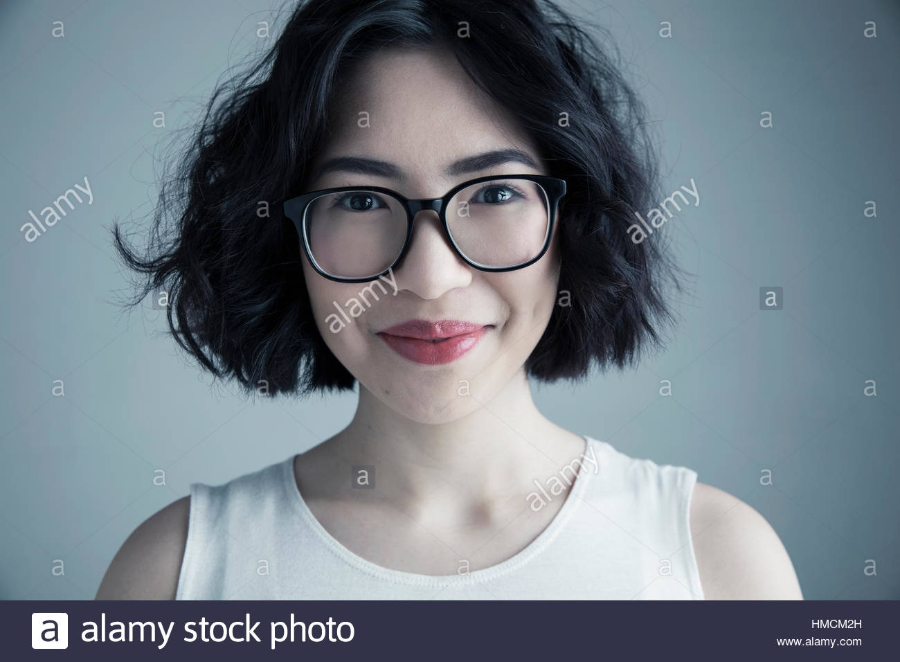 Close up portrait smiling mixed race young woman with black hair and eyeglasses Stock Photo