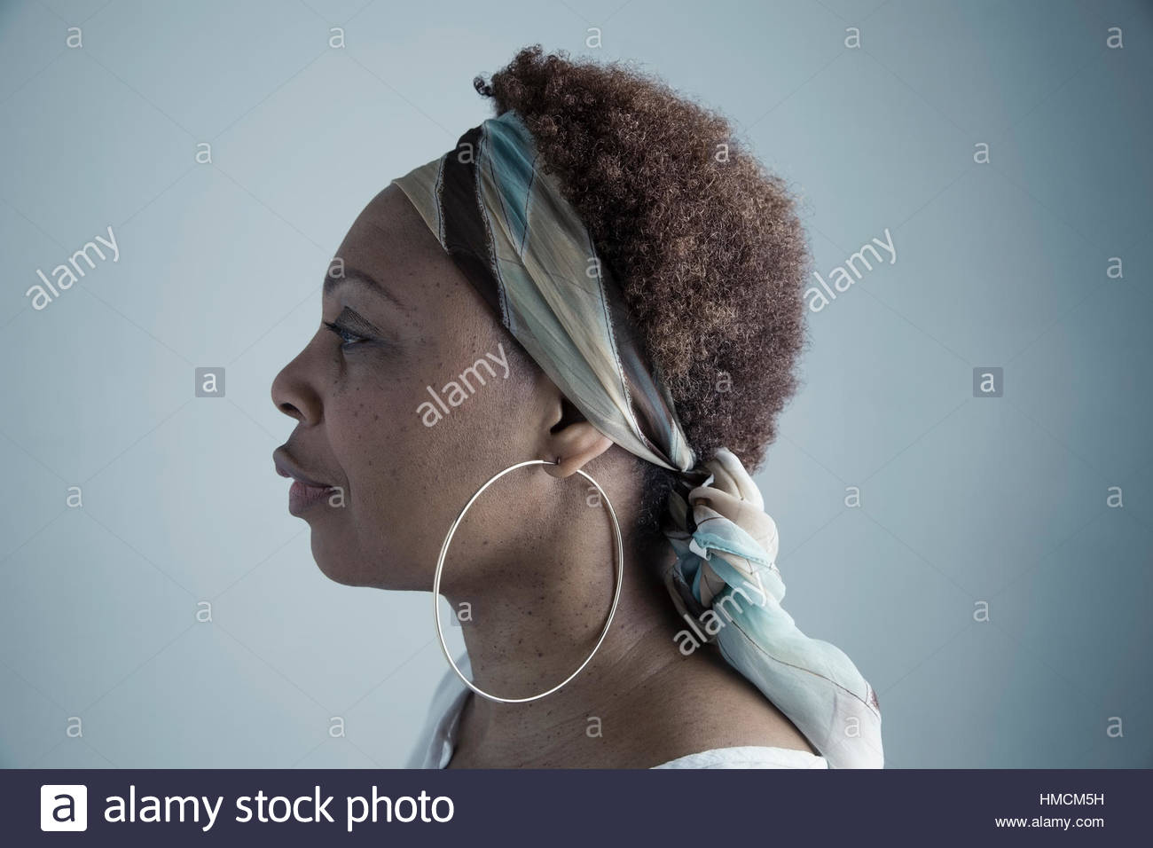 Profile portrait serious African American mature woman wearing headscarf and large hoop earrings Stock Photo
