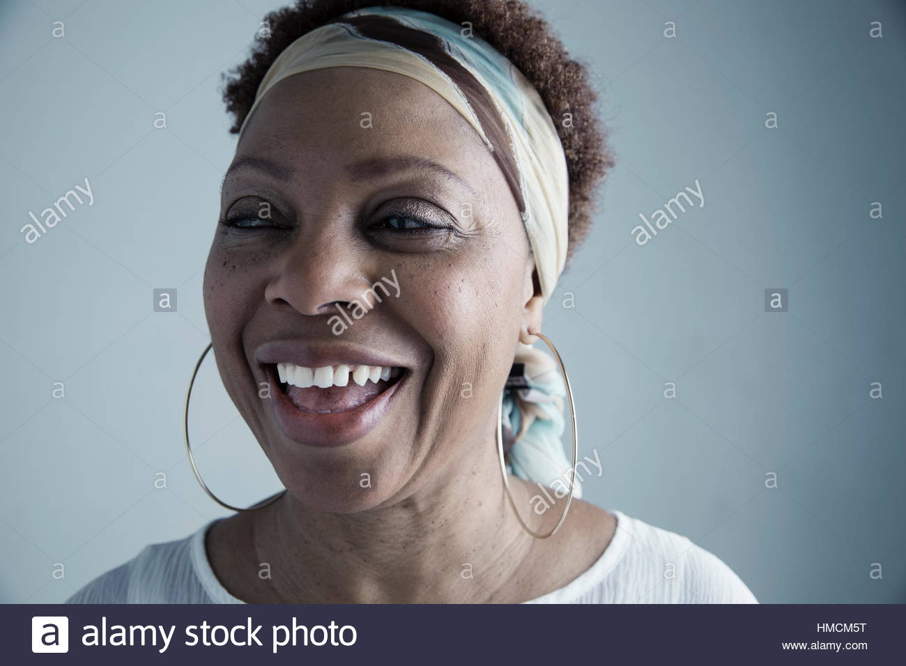 Portrait laughing African American mature woman wearing headscarf and large hoop earrings, looking away Stock Photo