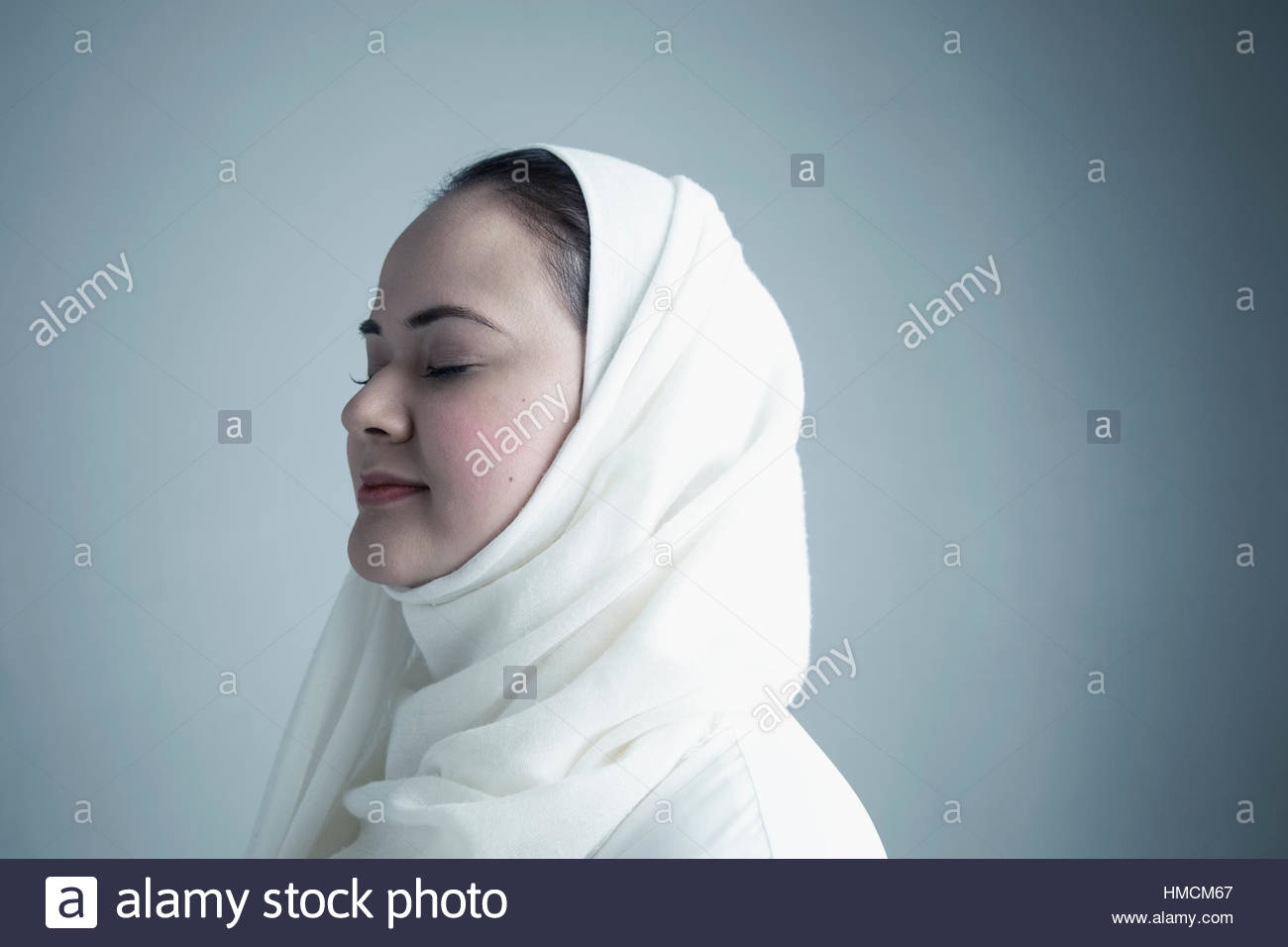 Portrait serene Middle Eastern young woman wearing white hijab with ...