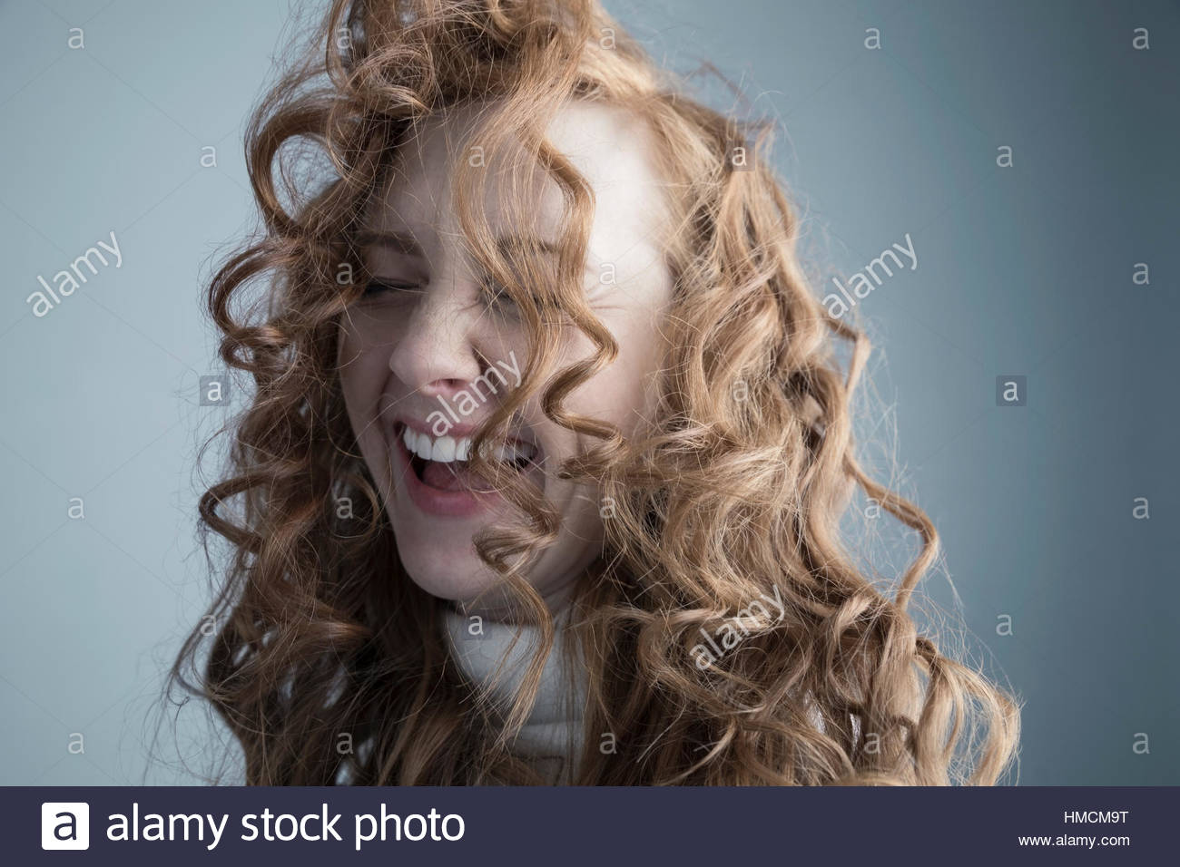 Portrait playful Caucasian woman with messy red curly hair in face Stock Photo