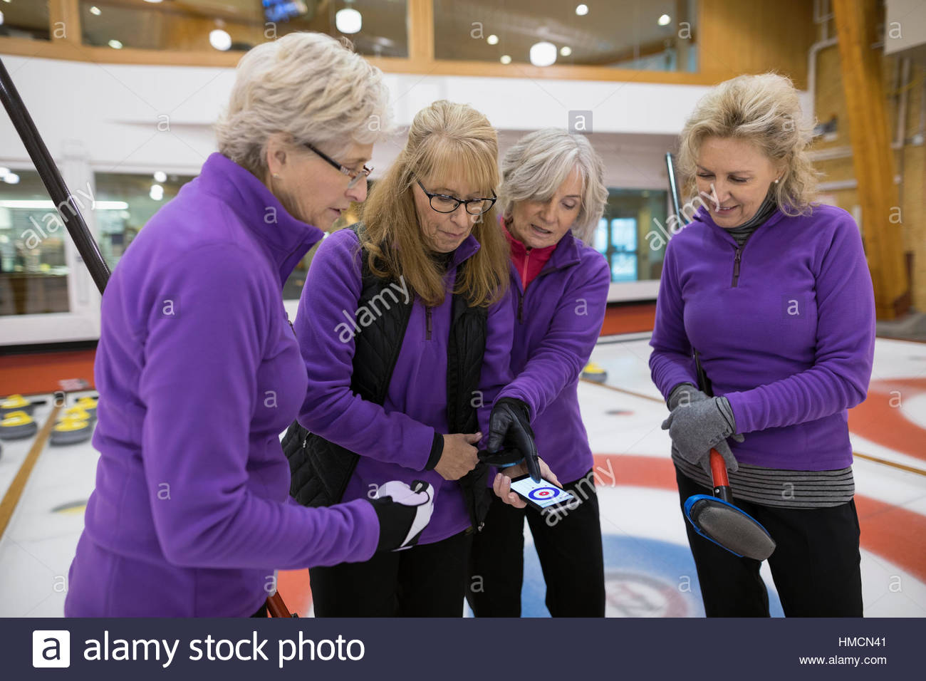 Senior women curling team scoring with mobile app on smart phone Stock Photo