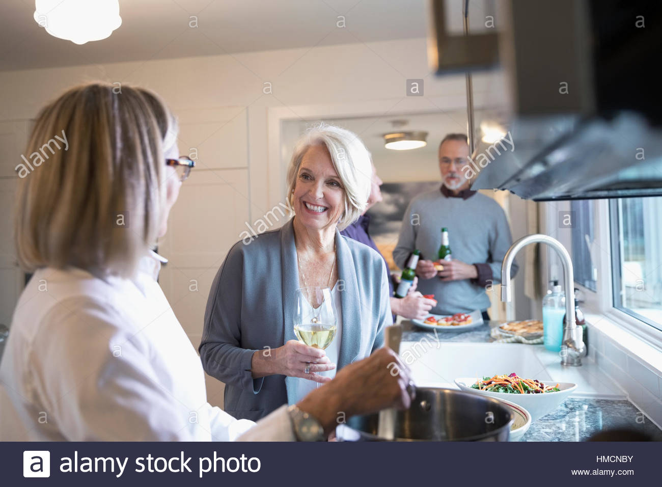 Senior women friends cooking and drinking wine in kitchen Stock Photo