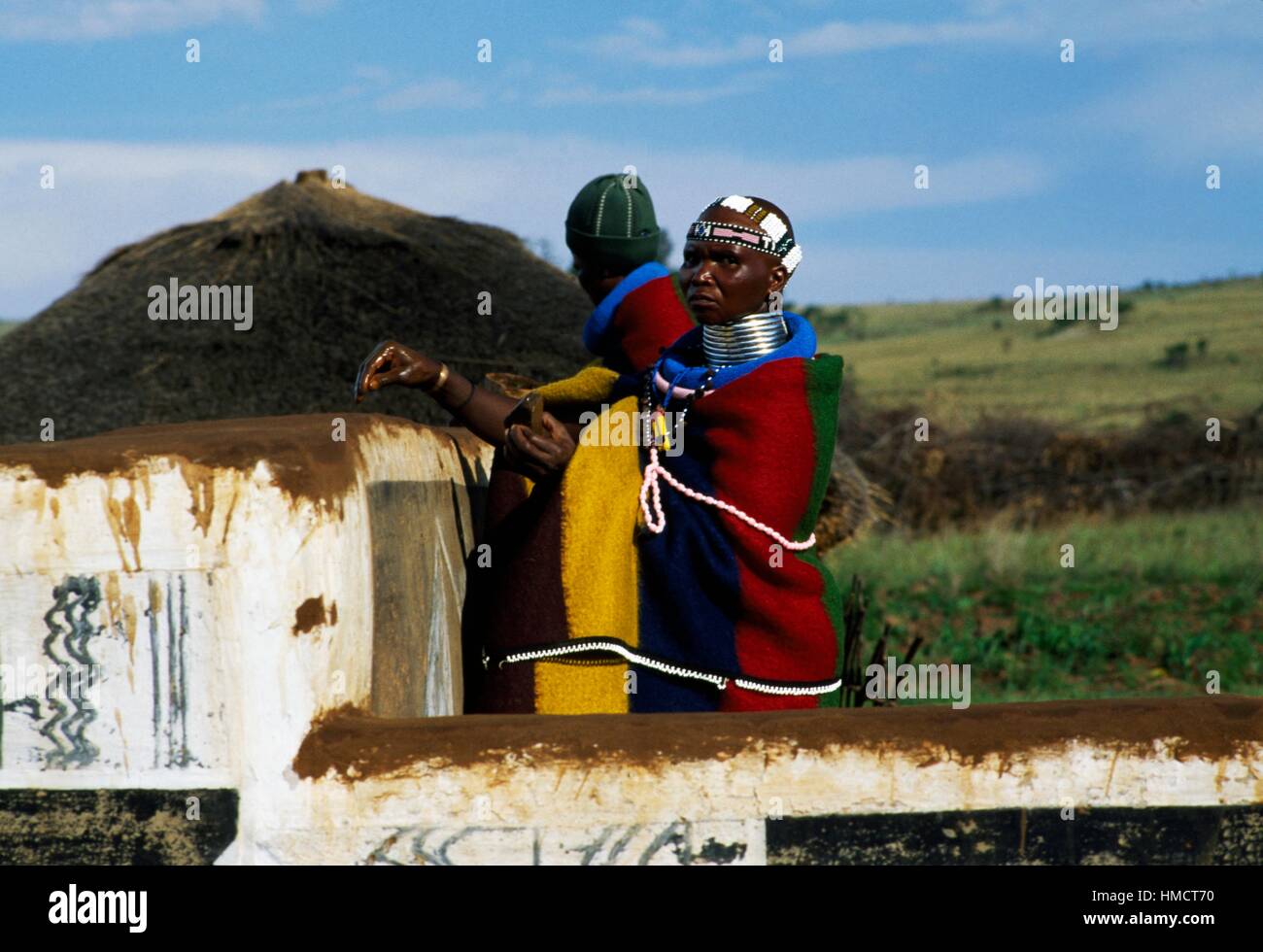 A Ndebele woman and a man decorating a rondavel (traditional round or oval house) in a village, South Africa. Stock Photo