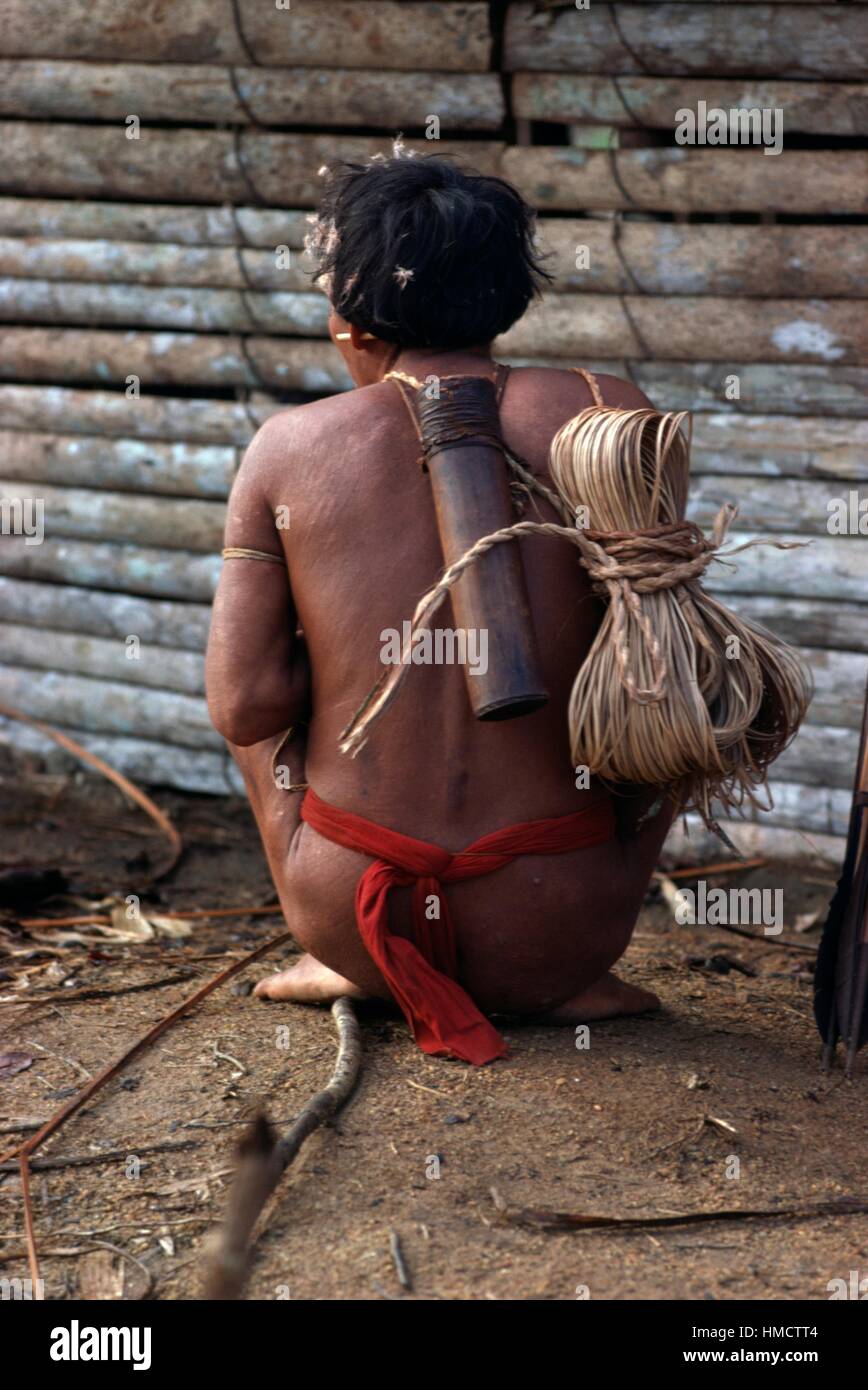 Yanomami person crouching with quiver and rope seen from behind, Venezuela. Stock Photo