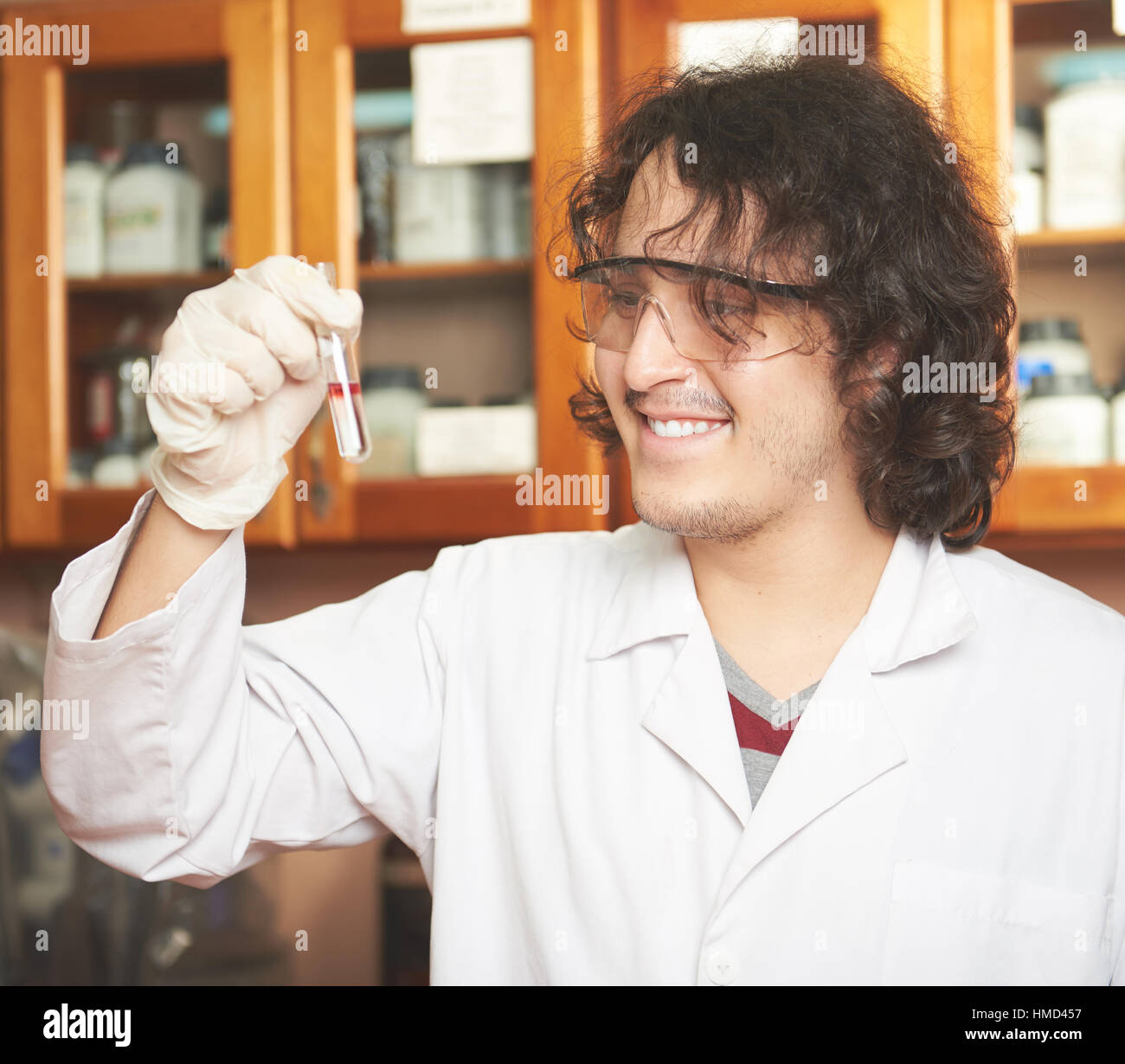 scientist smiling while looking at glass tube in lab Stock Photo