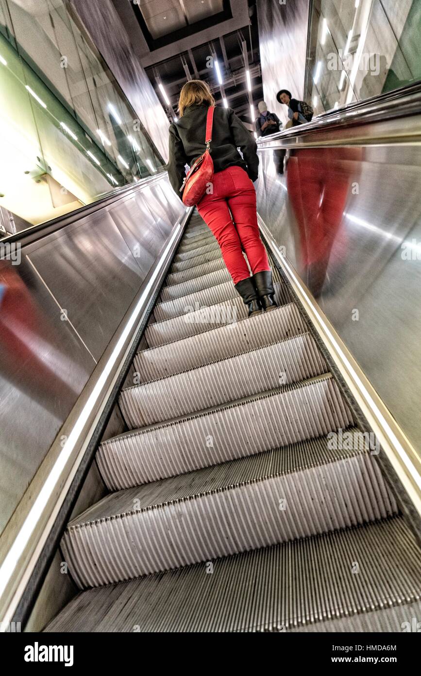 Young Woman in Fitted Red Pants going up an escalator. London, England, UK. Stock Photo