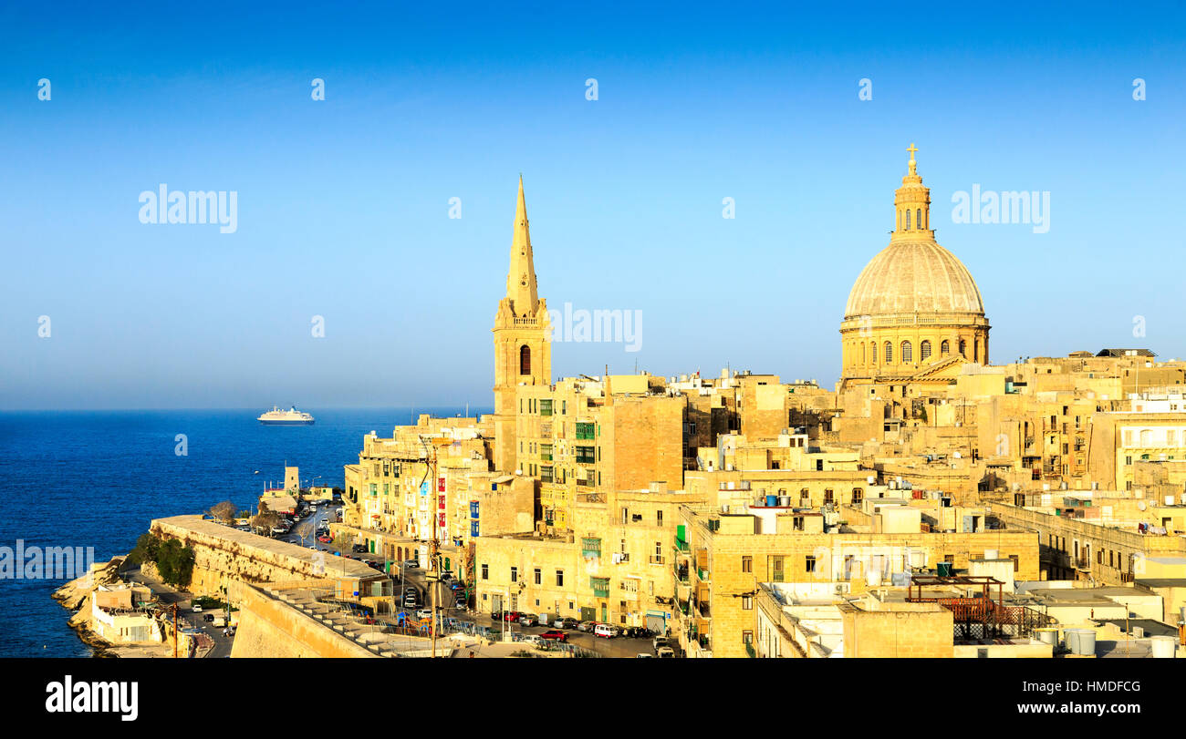 view of valletta old town, malta with a cruise ship in the distance  and St Pauls Anglican Cathedral and Our Lady of Mount Carmel church Stock Photo