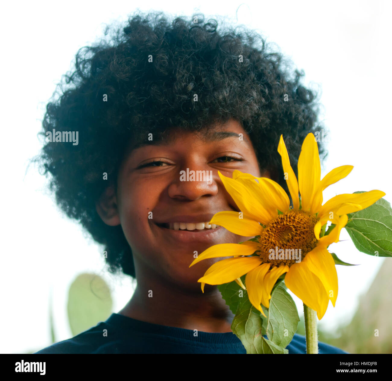 young boy smiles happily while holding a sunflower in his hand that has ...