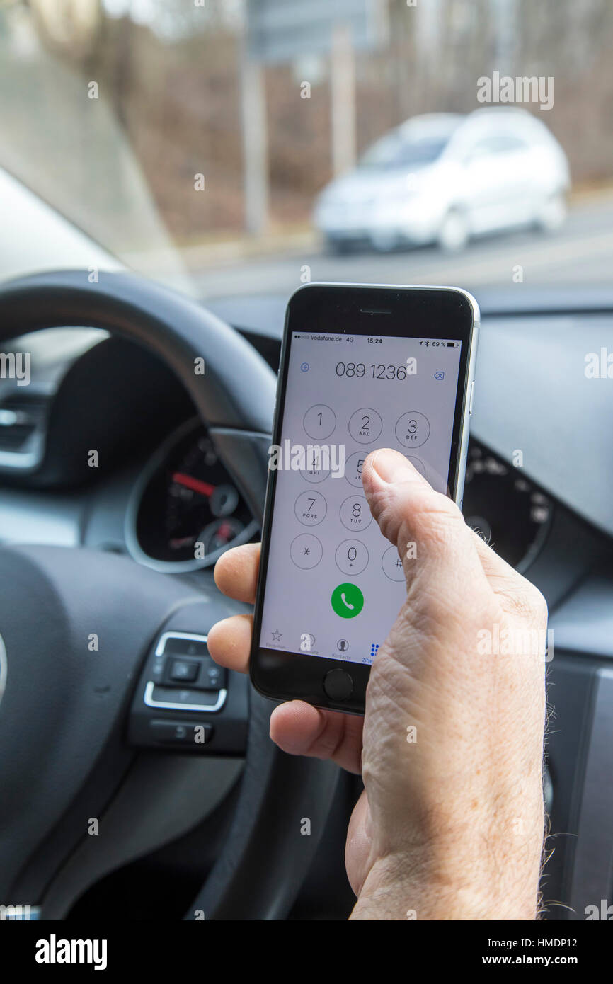 A car driver is using a mobile phone, smartphone, while driving the car