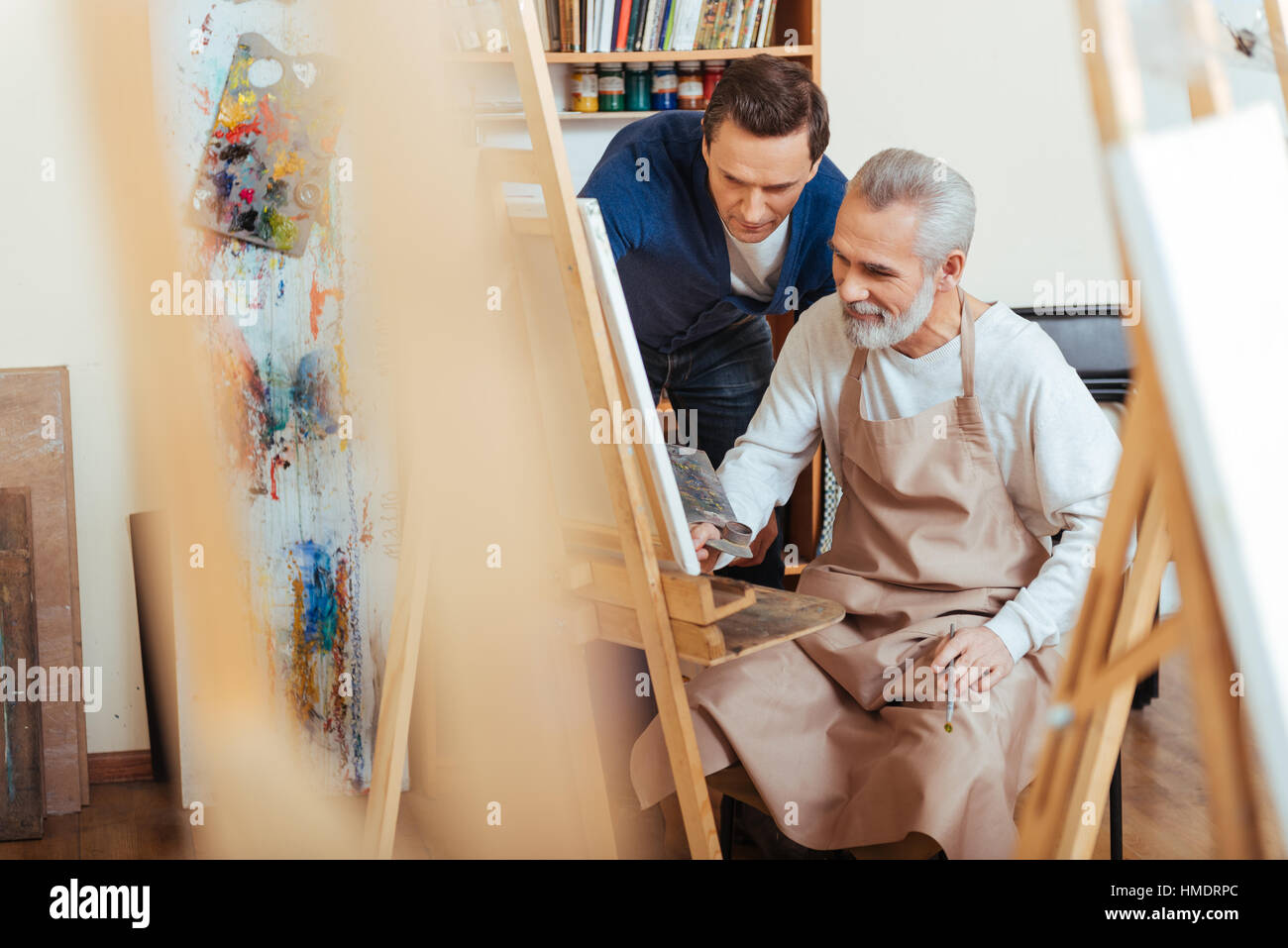 Handsome artist helping elderly man in painting Stock Photo