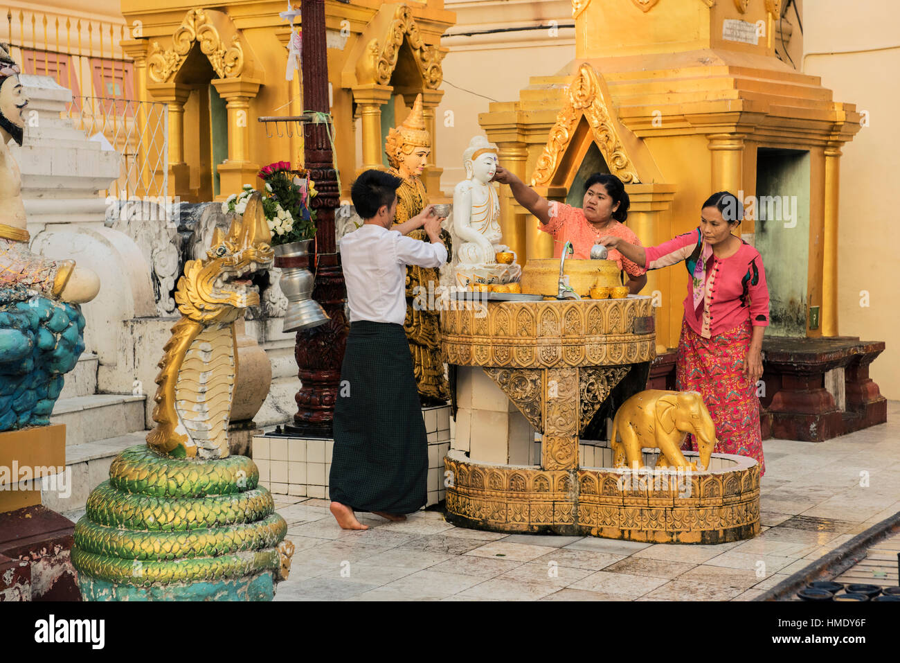 Devotees of the Buddha in traditional burmese dress worship at one of the Temples in the Shwedagon Pagoda Stock Photo