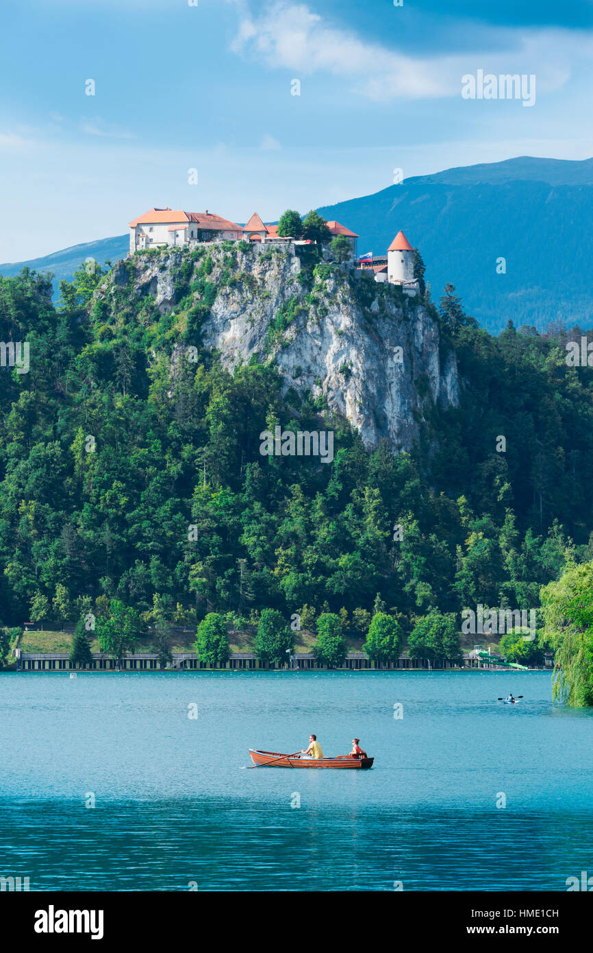 Lake Bled, Upper Carniola, Slovenia.  Bled Castle seen across the lake. Couple enjoying outing in rowing boat. Stock Photo