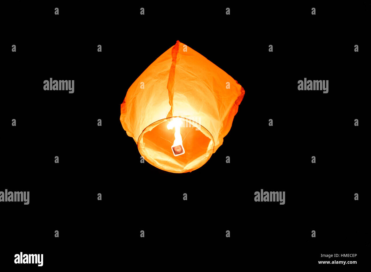 Orange paper sky flaming lantern, flying lantern, floating lantern, hot-air balloon is flying with a candle flame in the night. Popular Celebration or Stock Photo