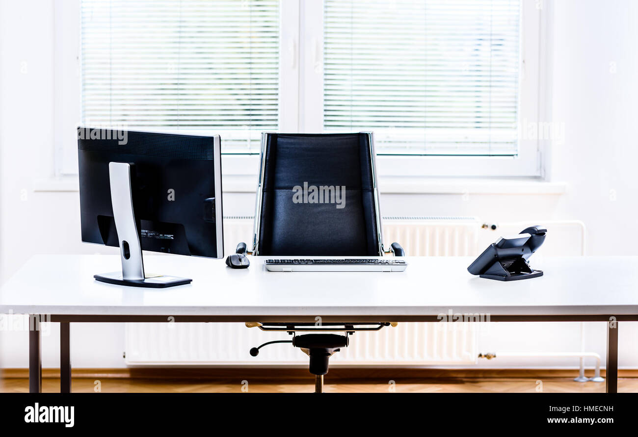 Modern empty office space desk with computer, phone and chair. Concept of corporate job vacancy, promotion, financial world and business in general. Stock Photo