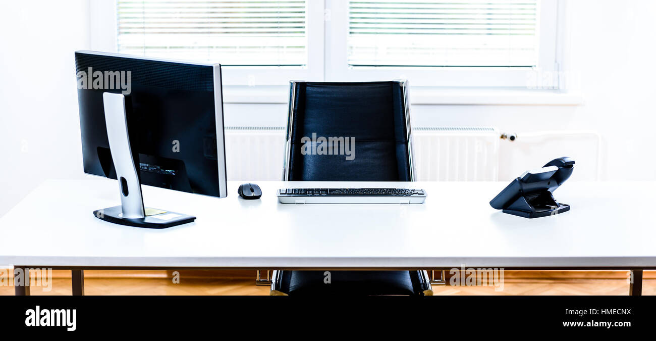 Modern empty office space desk with computer, phone and chair. Concept of corporate job vacancy, promotion, financial world and business in general. Stock Photo