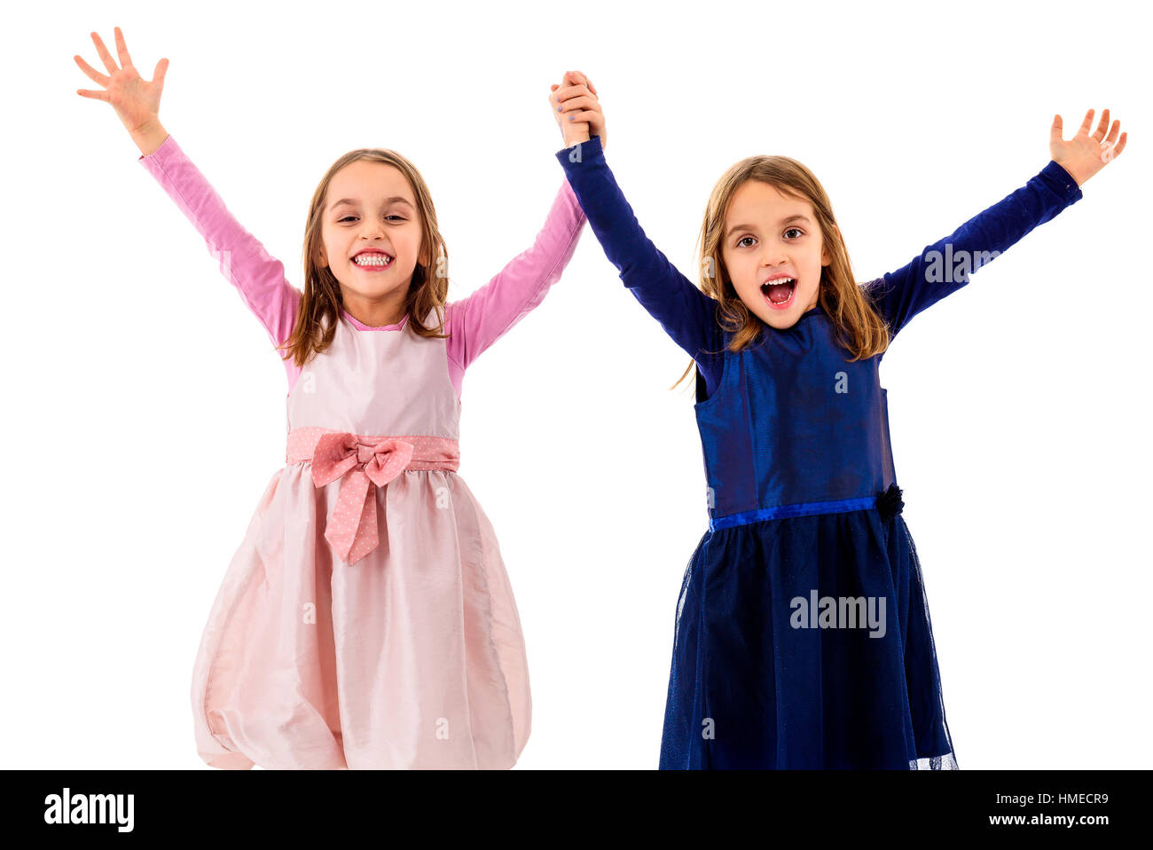 Twin girls are celebrating with hands risen holding hands. Children victorious and excited with their achievement and accomplishment. Reaching their g Stock Photo