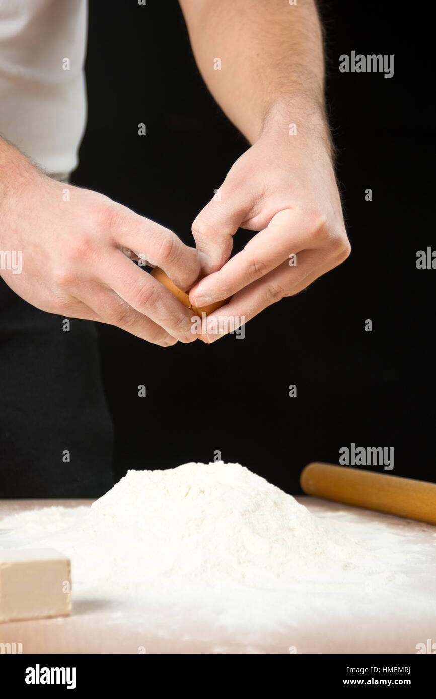 Man breaking egg on flour. Dough making started Stock Photo