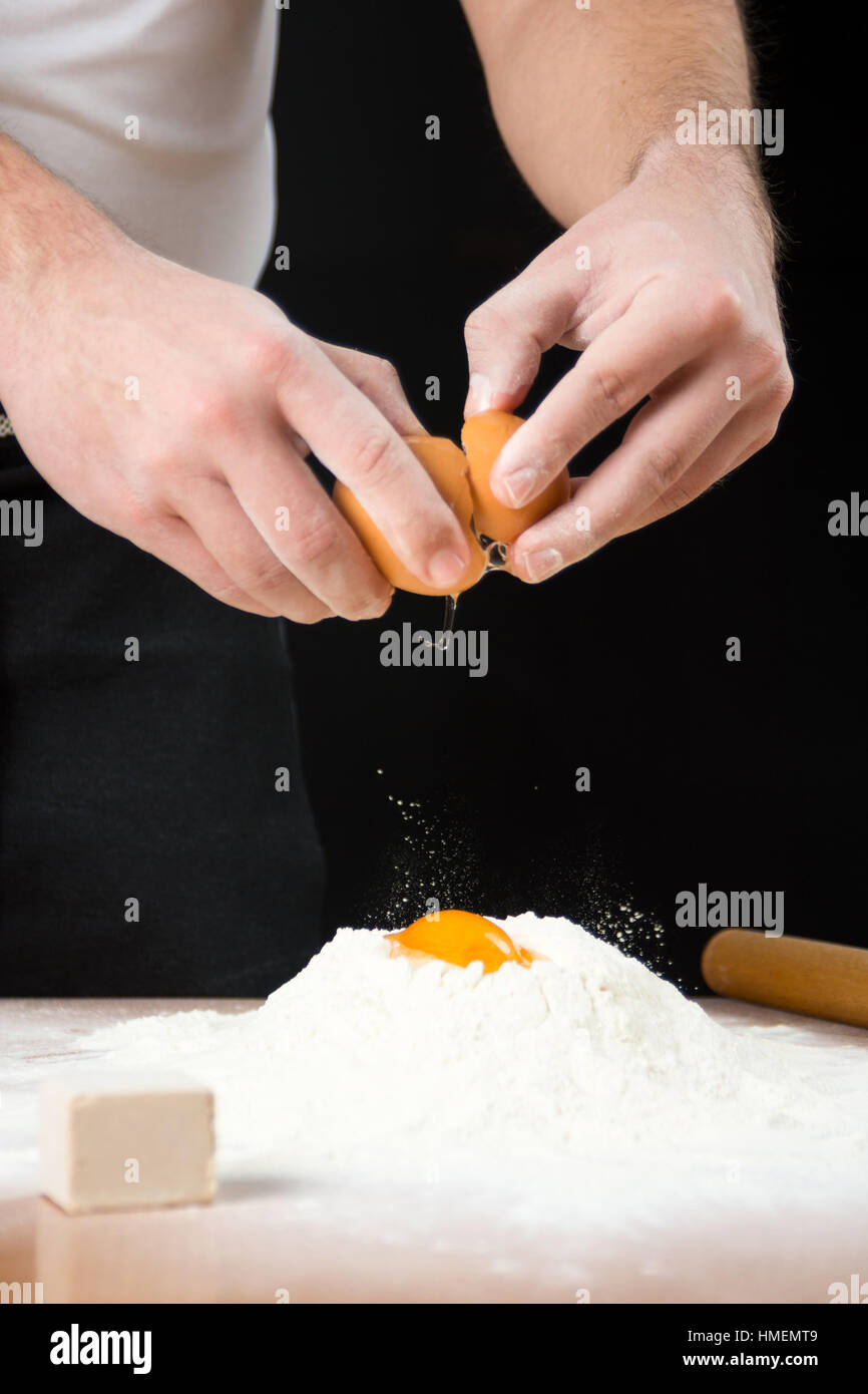 Man breaking egg on flour. Dough making started Stock Photo