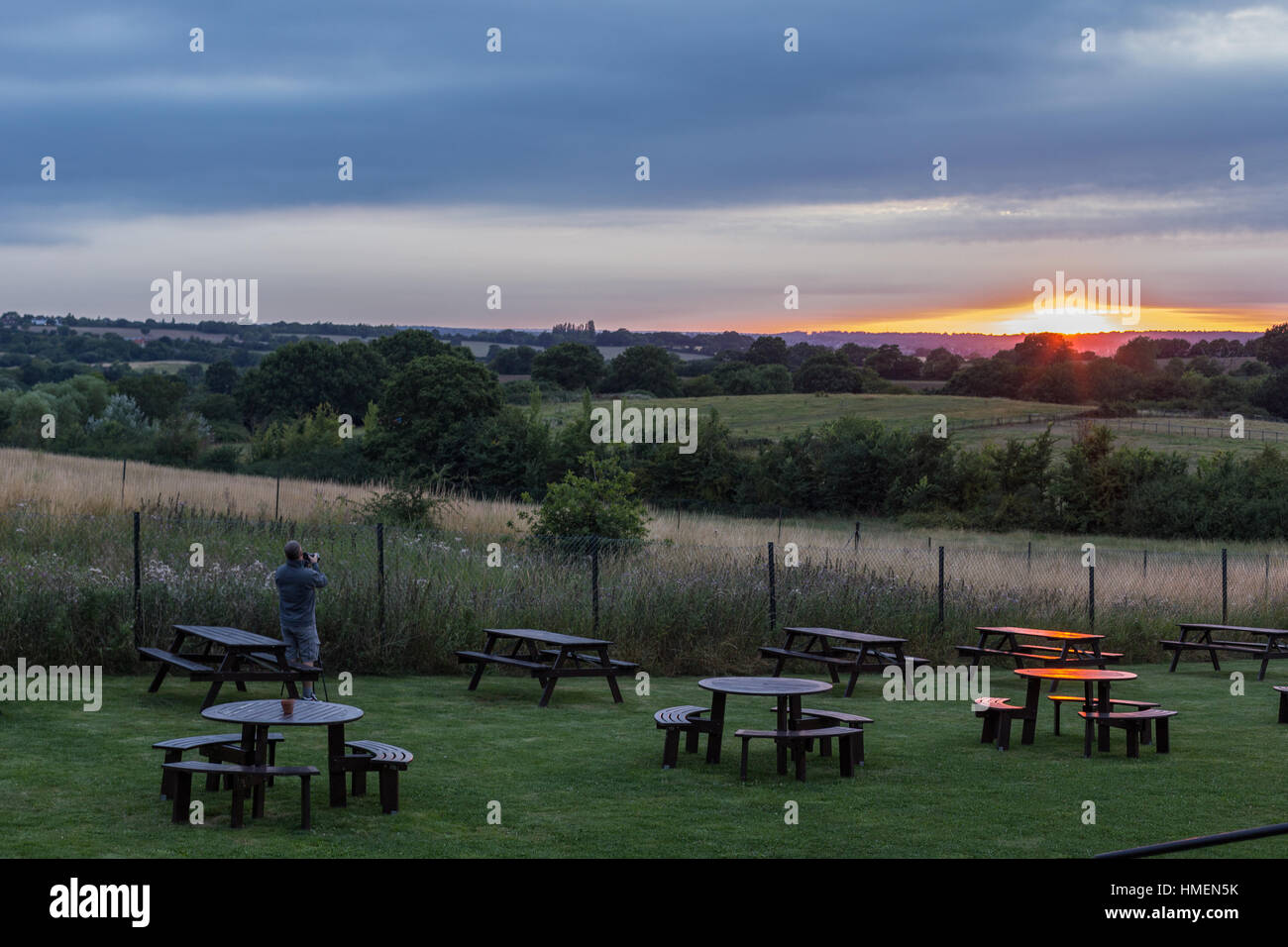 Sunset looking over the Essex countryside and shows a photographer taking a picture of the sunset. Taken on a late summer's evening. Stock Photo