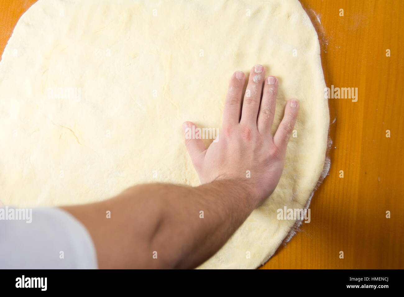 Male baker spreading the dough for making pizza Stock Photo