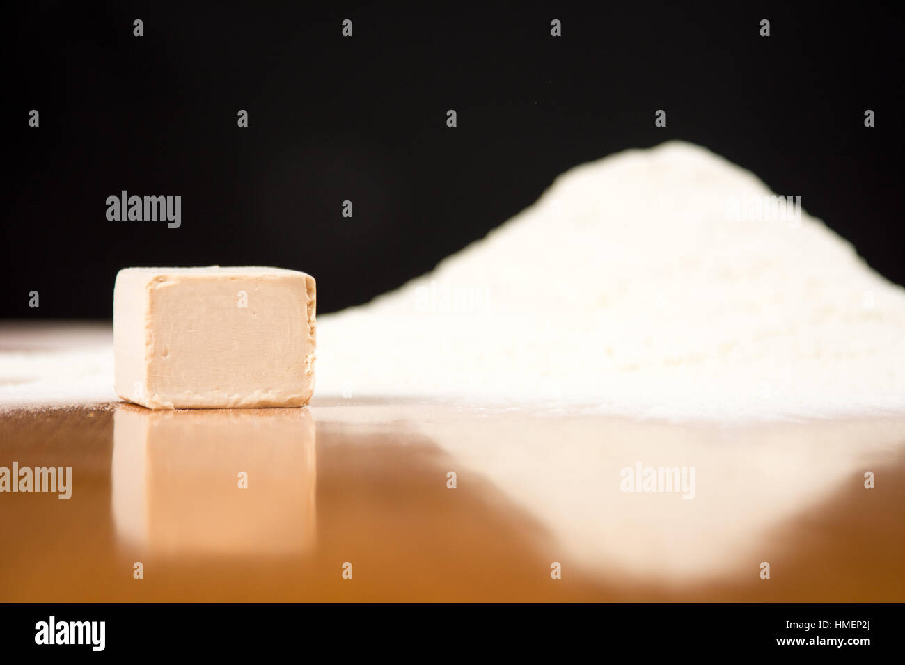 Yeast cube and flour pile on a baking table Stock Photo
