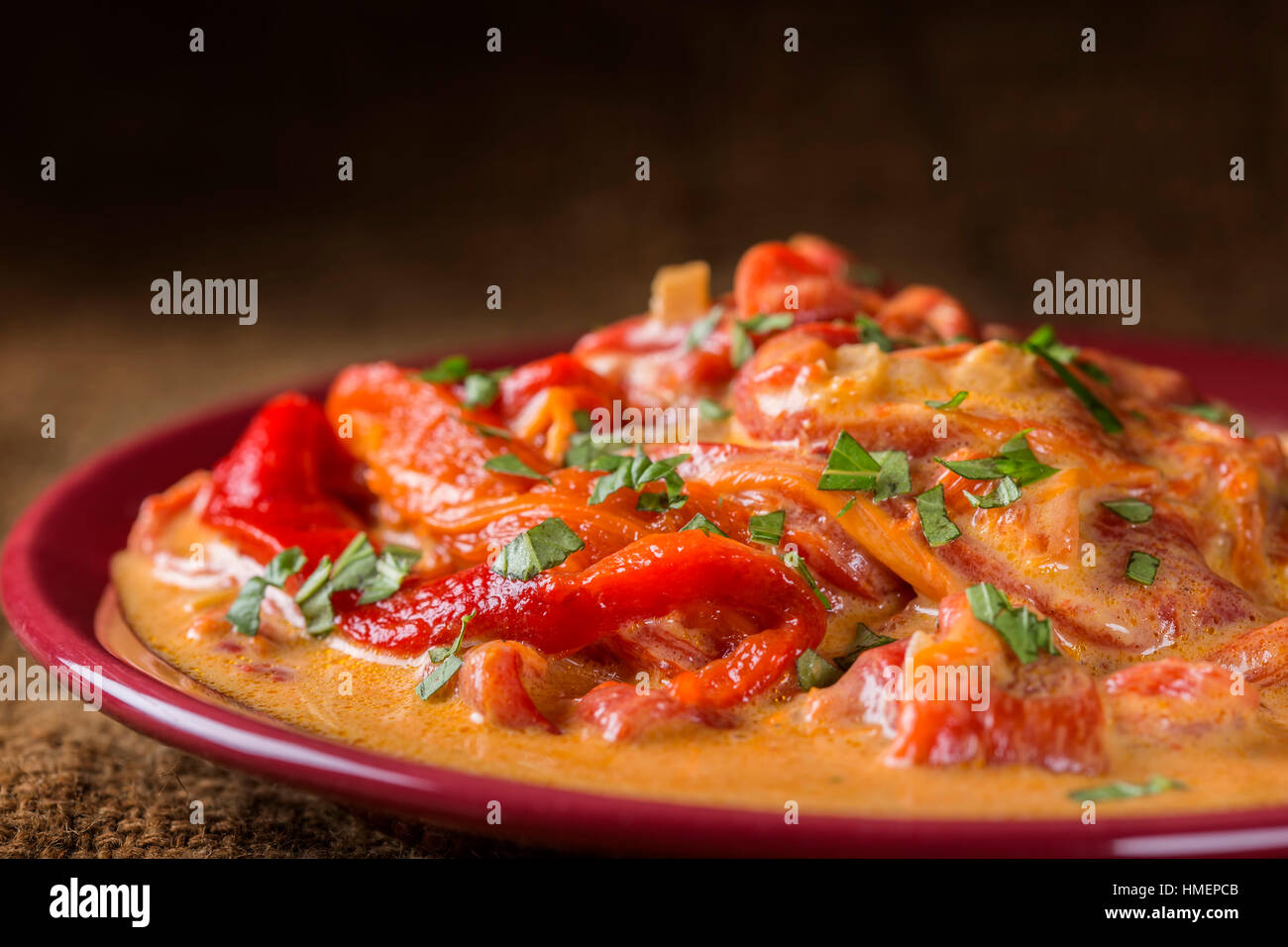 Stew made from backed red peppers with sour cream and parsley on plate Stock Photo