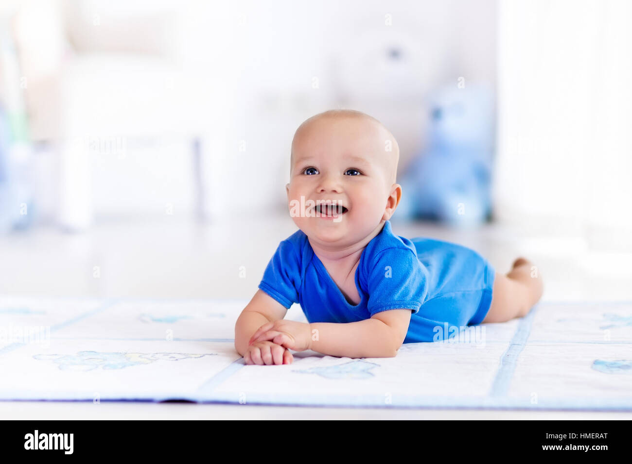 Cute baby boy on colorful playmat and gym, playing with hanging rattle toys. Kids activity and play center for early development Stock Photo