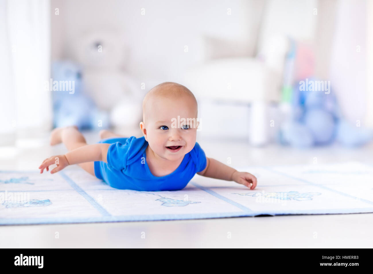 Cute baby boy on colorful playmat and gym, playing with hanging rattle toys. Kids activity and play center for early development Stock Photo