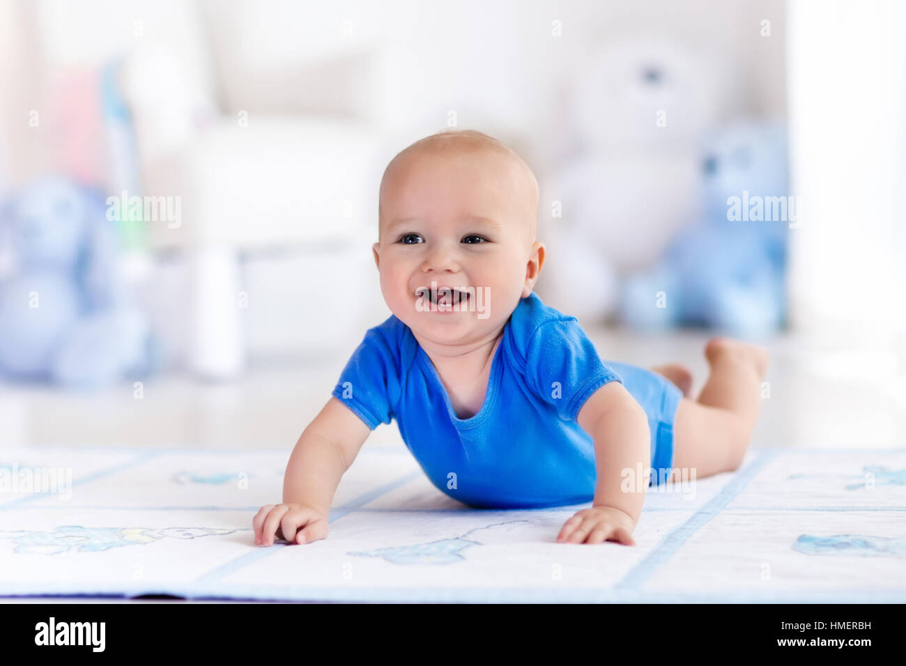 Cute baby boy on colorful playmat and gym, playing with hanging rattle toys. Kids activity and play center for early development Stock Photo