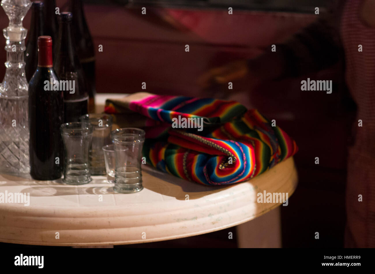 Colourful wayu, a Bolivian llama wool blanket, on a table next to a carafe, a bottle of red wine and some glasses Stock Photo