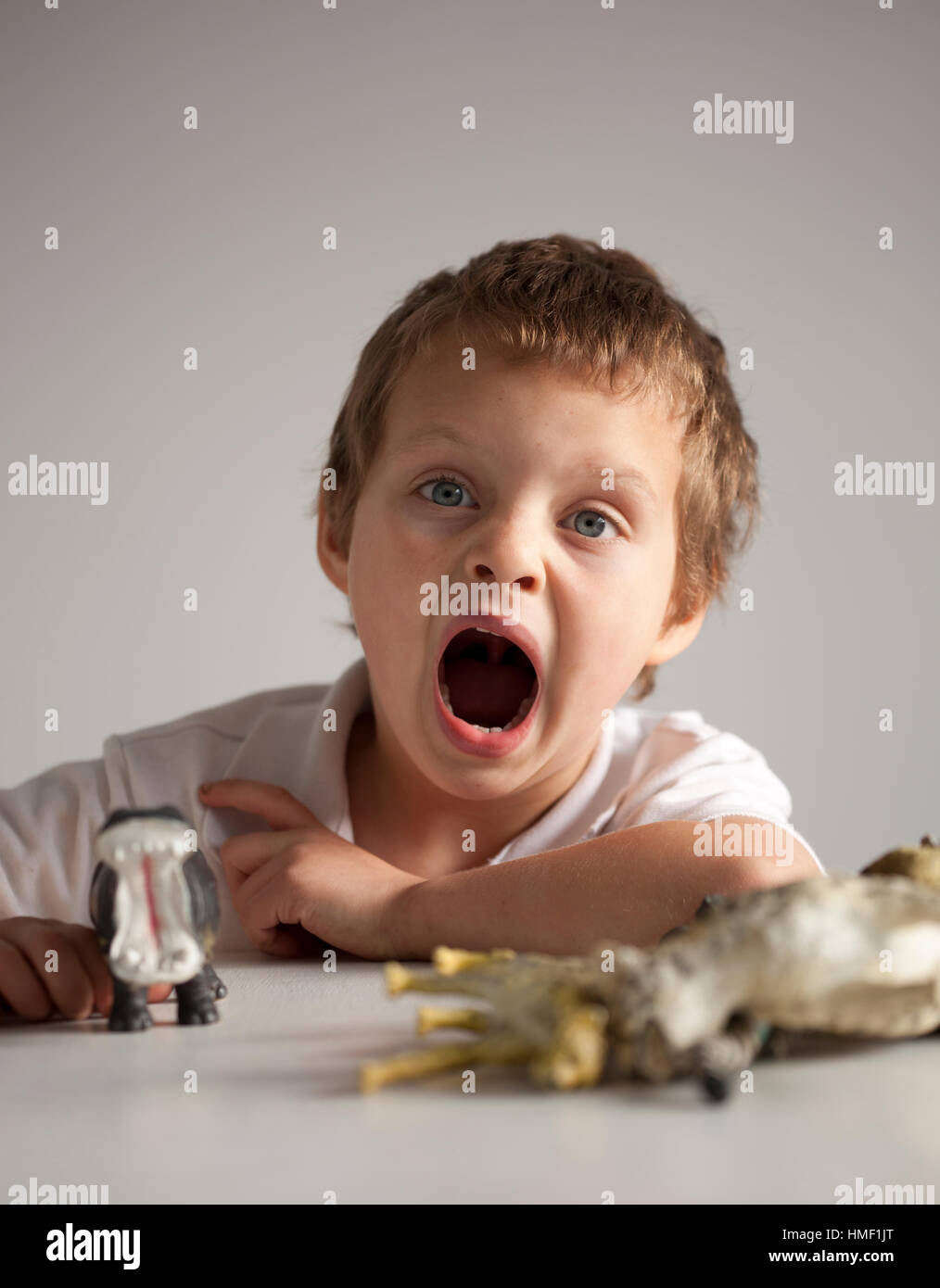 A four year old boy imitates the open mouth of his model hippo Stock Photo