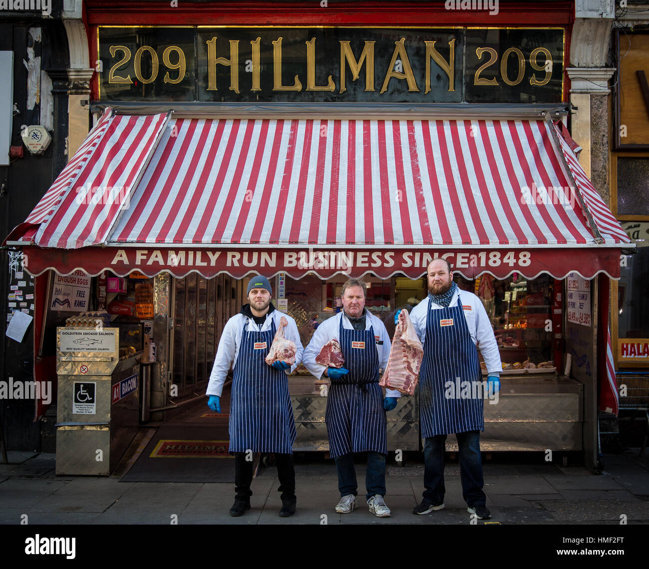 Butchers pose outside their butcher shop in London Stock Photo