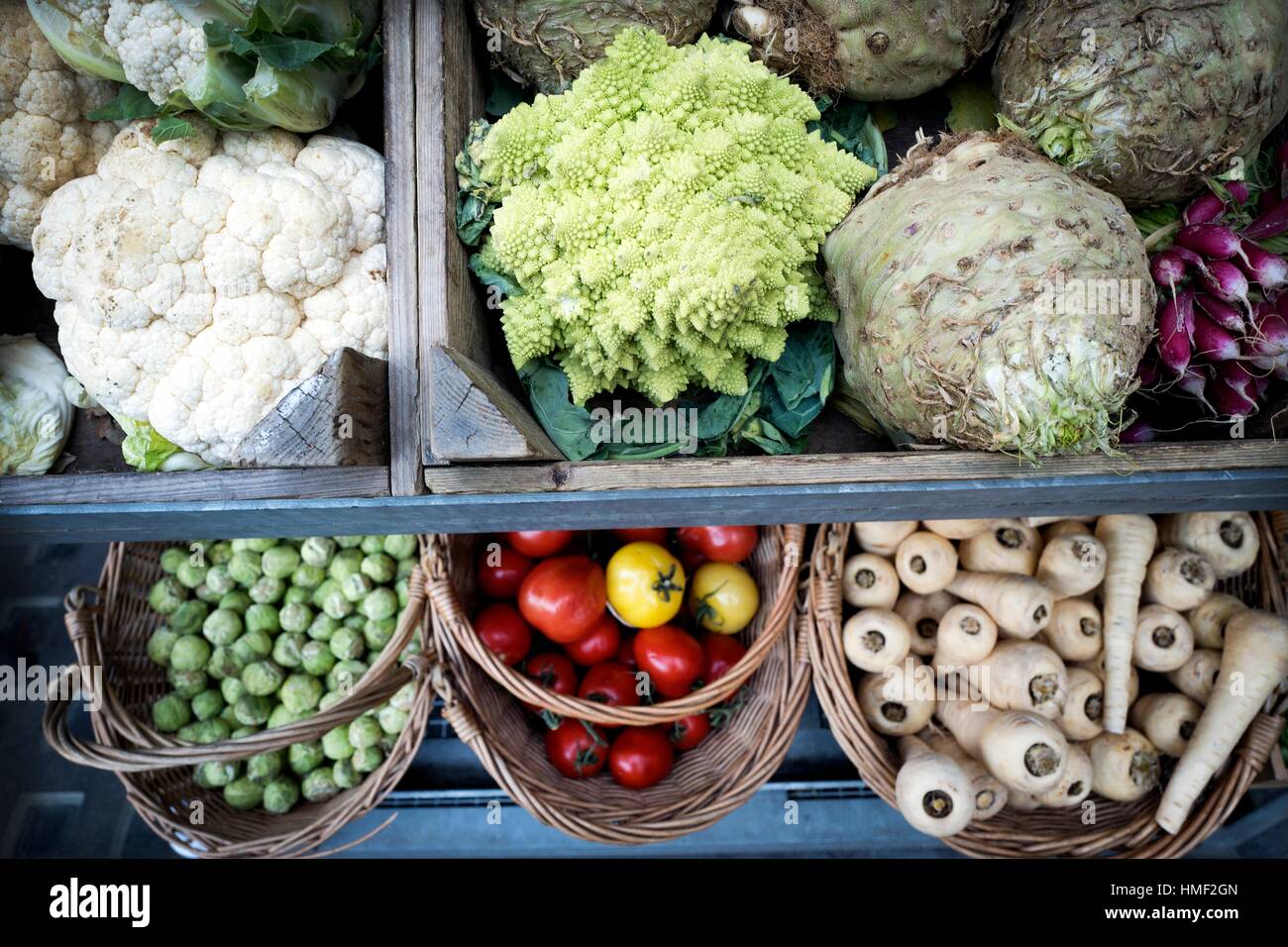 Organic vegetables in wooden crates and baskets radishes, tomatoes