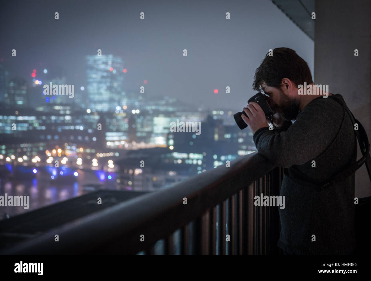 A man takes a photograph from the balcony of the Tate Modern Switch House in London Stock Photo