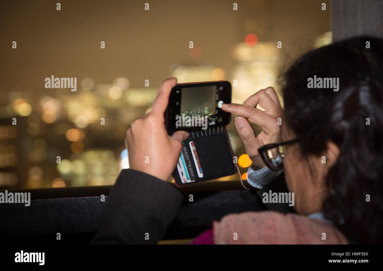 A woman takes a photograph from the balcony of the Tate Modern Switch House in London Stock Photo