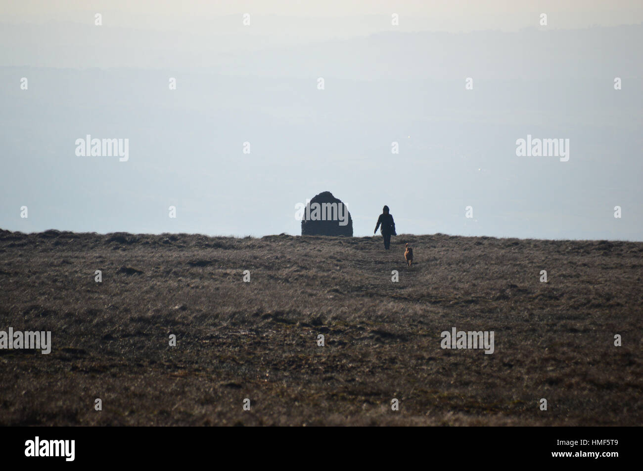 Woman Walking Dog by the Dry Stone Scout Bee Hive Memorial on Pendle Hill. Lancashire England UK. Stock Photo