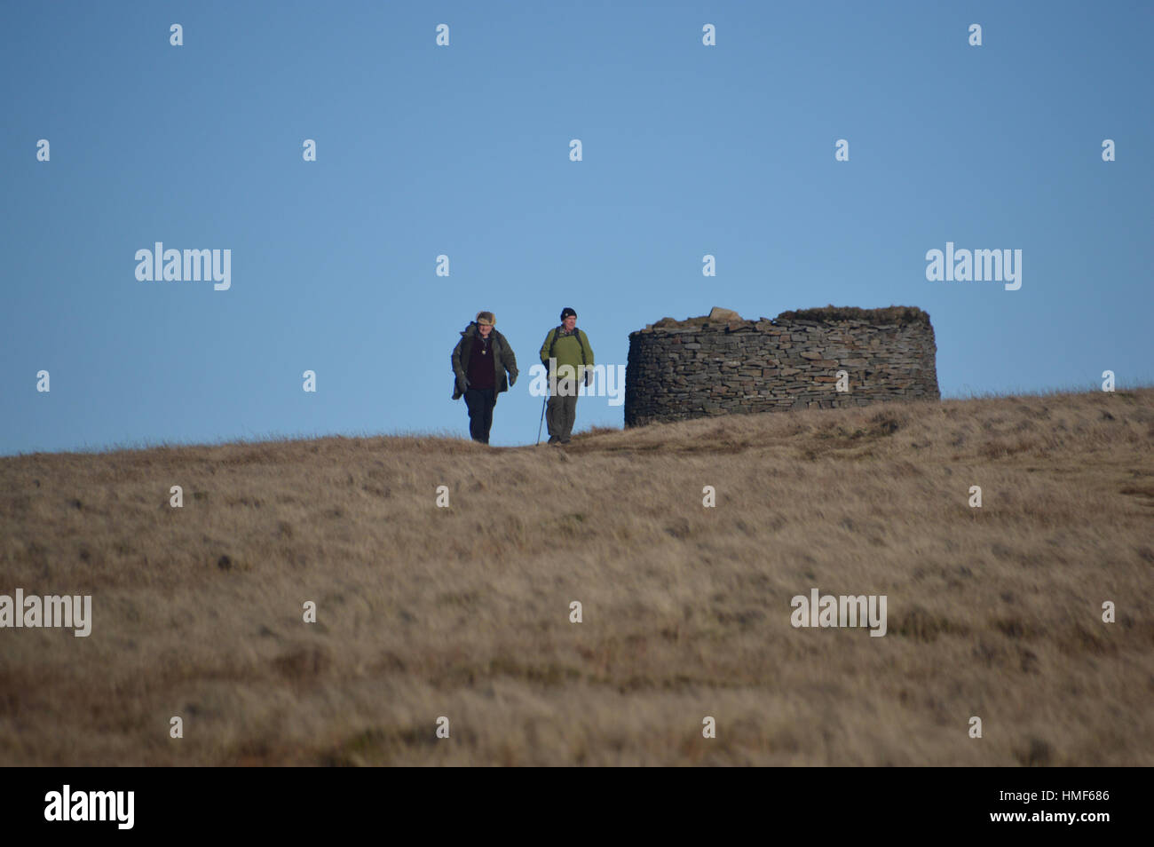 Two Elderly Fellwalkers Walking from the Dry Stone Shelter on Pendle Hill. Lancashire England UK. Stock Photo