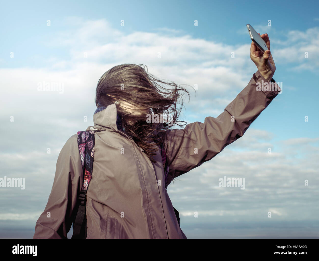 A woman trying to take a selfie on a windy day Stock Photo