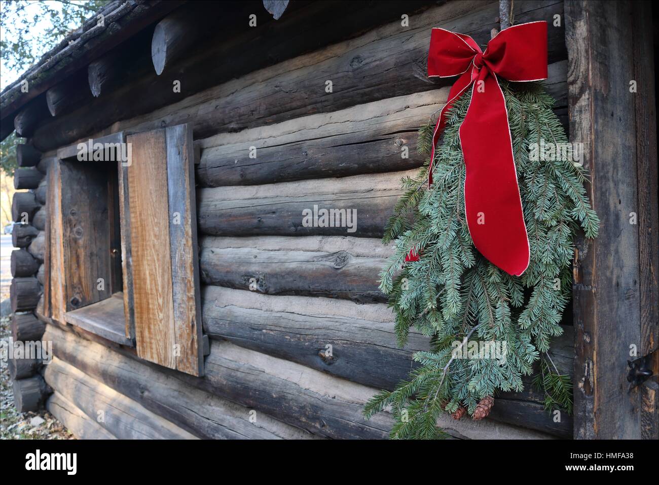 A log cabin wears a pretty red bow just in time for Christmas, in