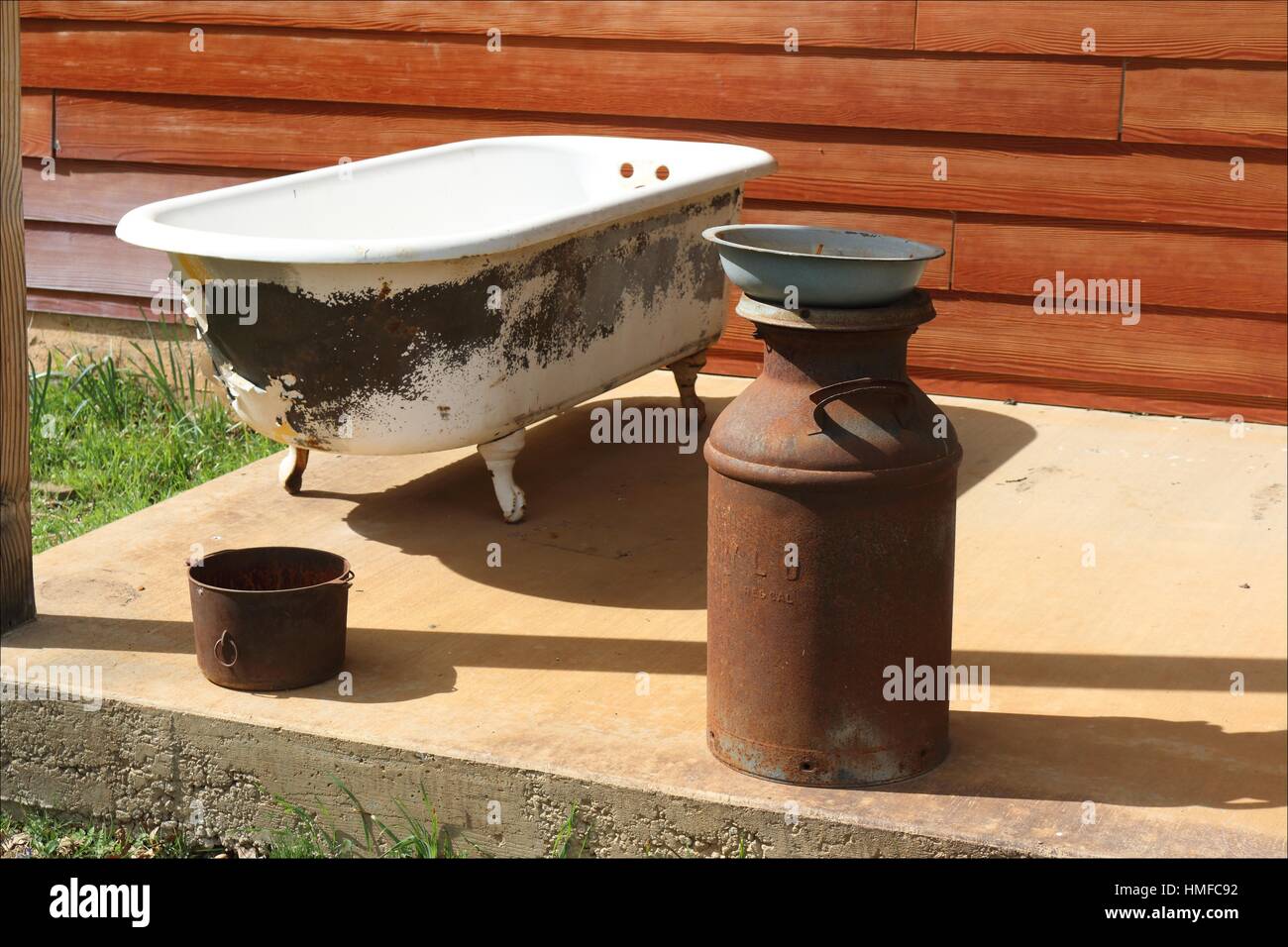 Old rusty antiques and an old claw foot tub decorate the porch of a
